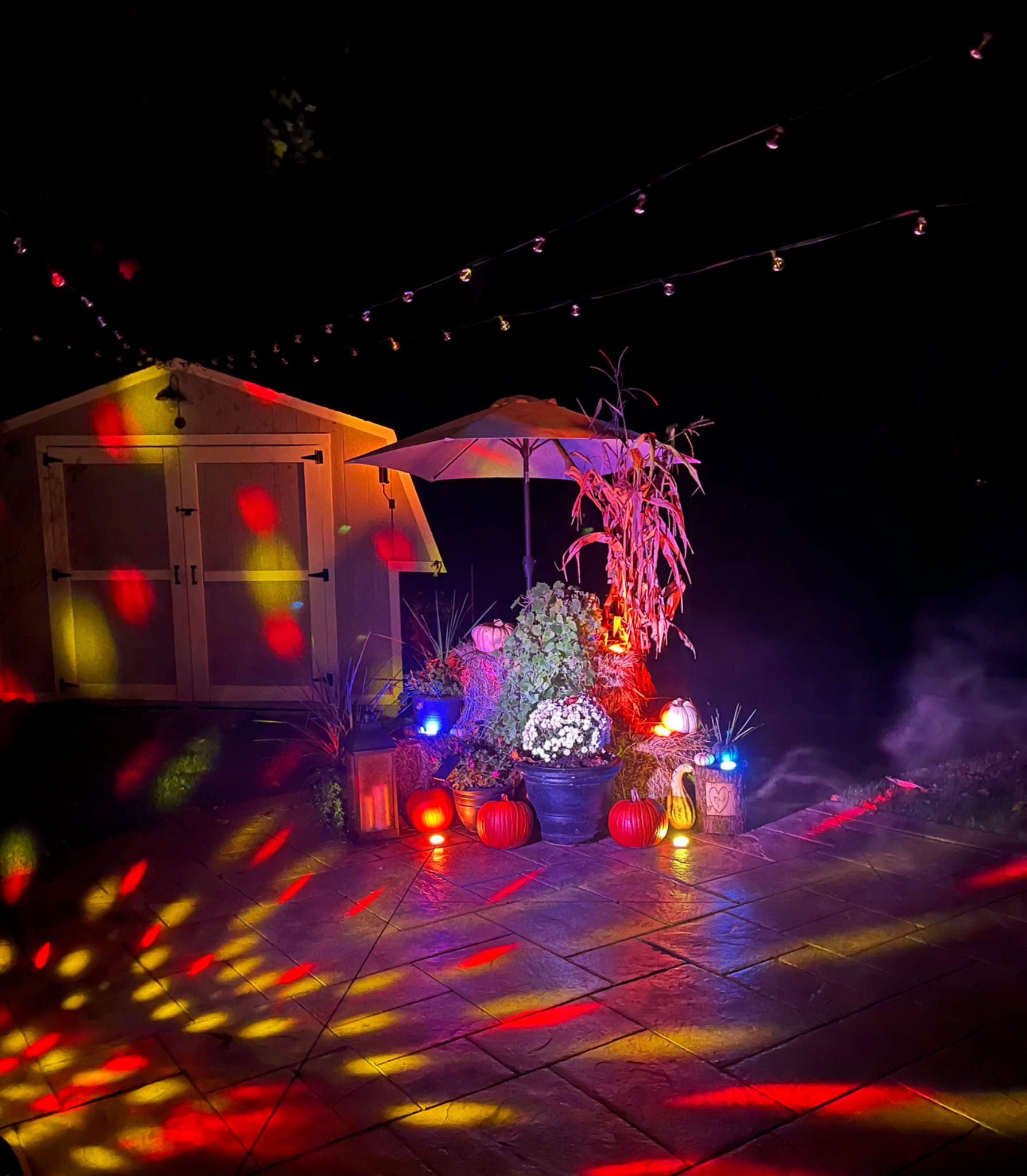 Colorful Halloween lighting and fog transforming a backyard patio at night