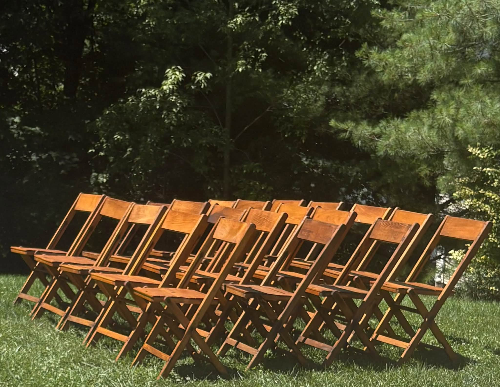 Rows of wooden folding chairs arranged outdoors on a lawn